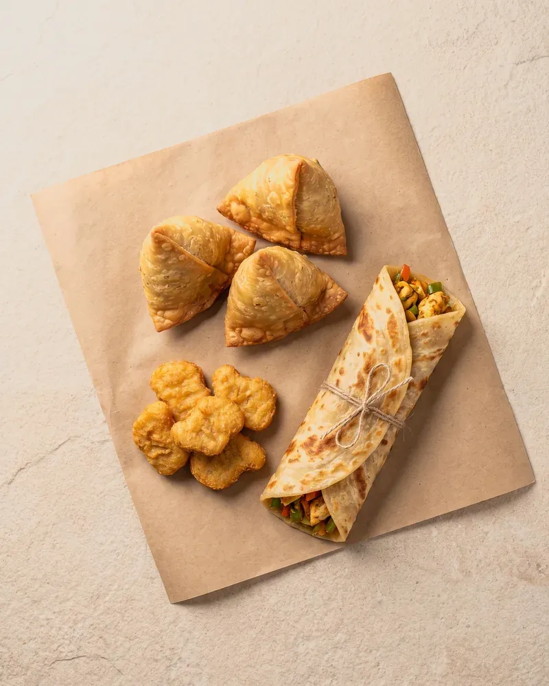 Samosas, chicken nuggets and a paratha roll on kraft paper